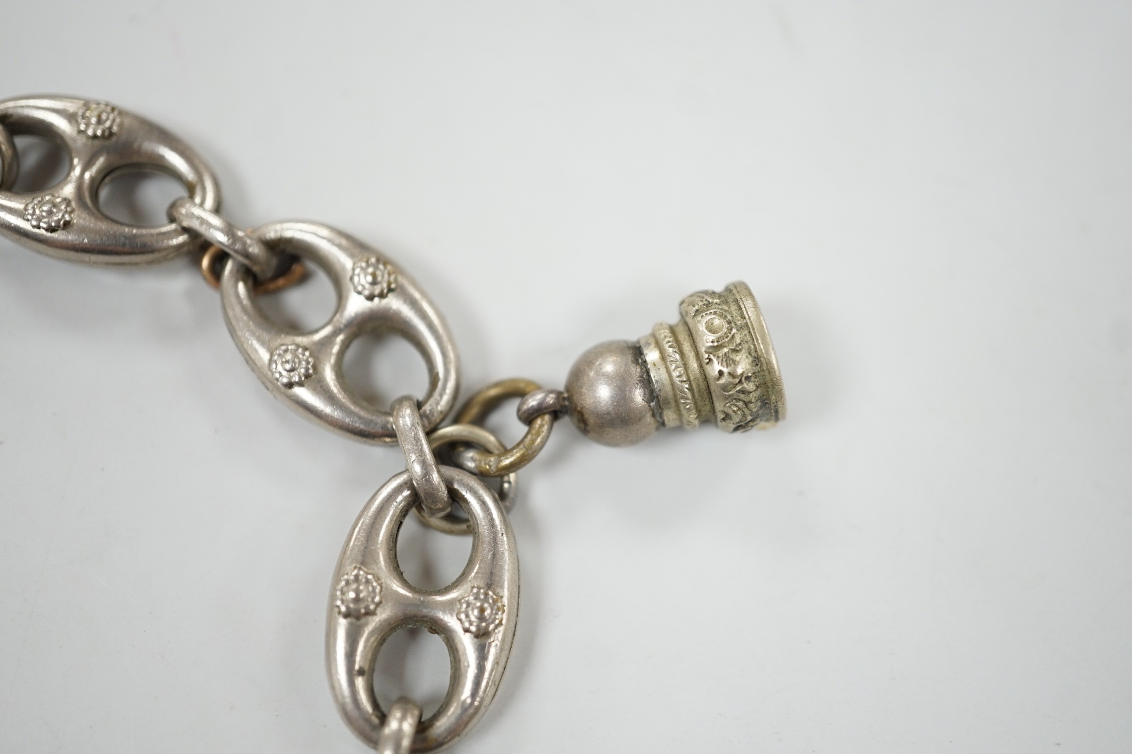 A white metal oval link bracelet, hung with three charms, including two fob seals, 21cm.